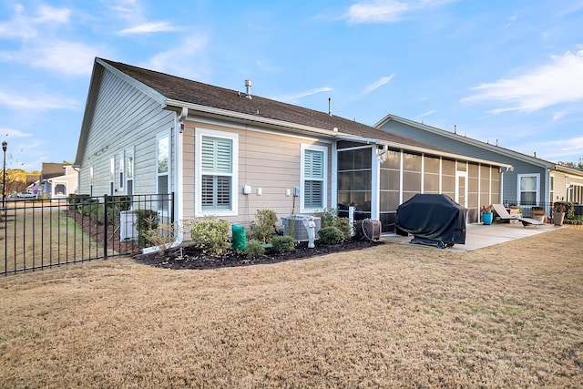 rear view of house with a yard, central AC, a patio area, and a sunroom