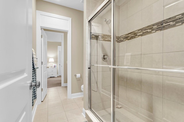 bathroom featuring toilet, tile patterned floors, and a shower with shower door