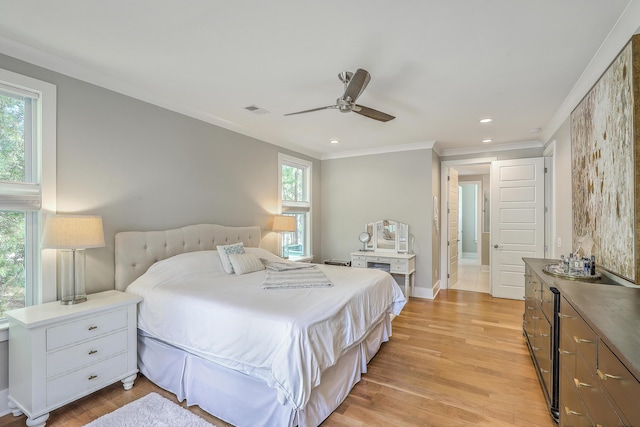 bedroom featuring ceiling fan, light wood-type flooring, and crown molding