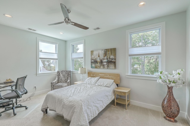 bedroom with light colored carpet, ceiling fan, and multiple windows