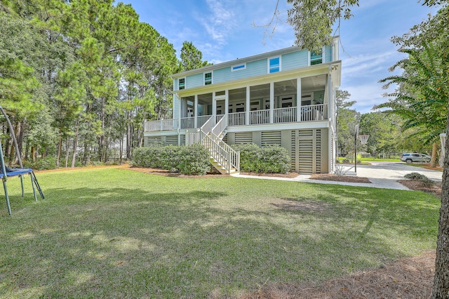 rear view of house featuring a porch, a yard, and a trampoline