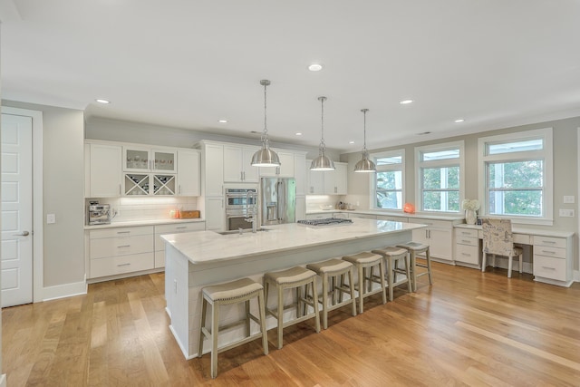 kitchen featuring appliances with stainless steel finishes, a spacious island, white cabinetry, decorative light fixtures, and tasteful backsplash