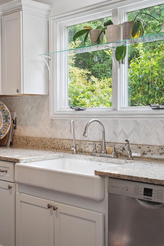 interior space with tasteful backsplash, dishwasher, a sink, light stone counters, and white cabinets