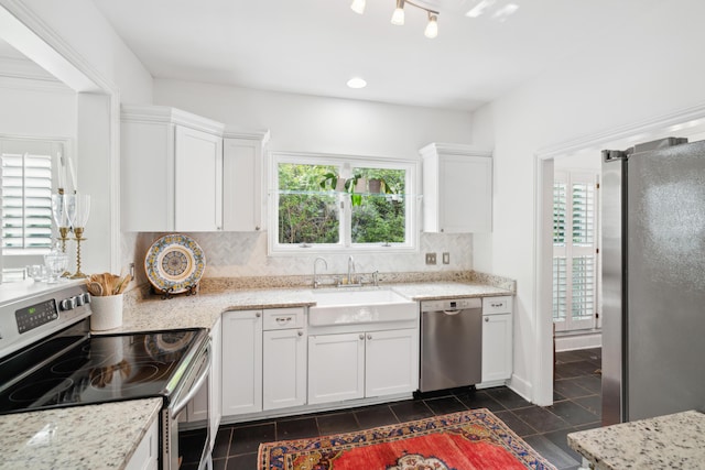 kitchen with backsplash, a sink, dark tile patterned flooring, stainless steel appliances, and white cabinetry