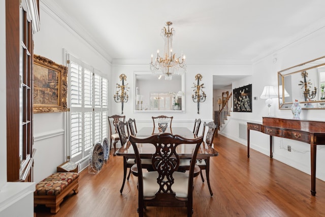 dining area featuring crown molding, a notable chandelier, wood finished floors, and stairway