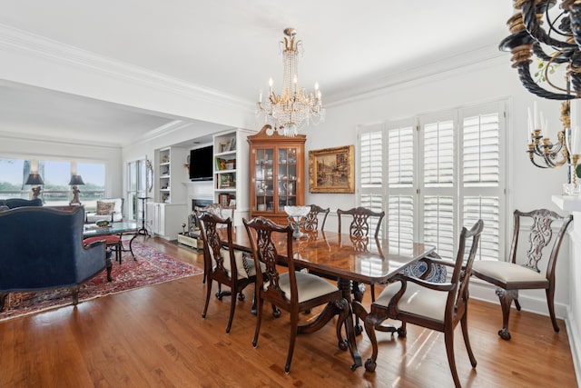 dining space with ornamental molding, built in features, wood finished floors, and a chandelier