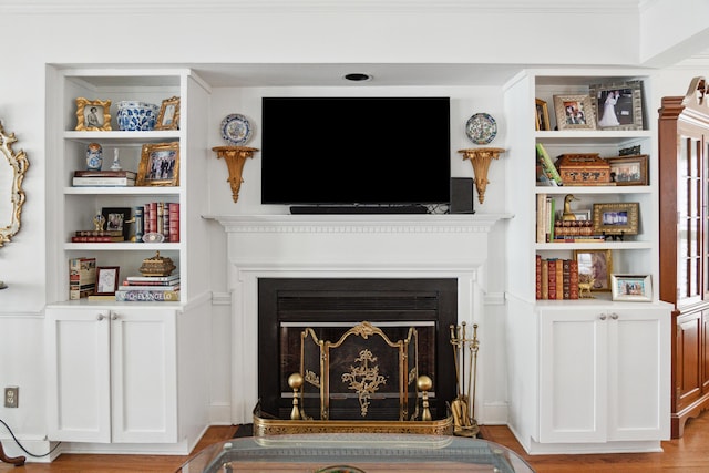 living room featuring built in shelves, light wood finished floors, and a fireplace
