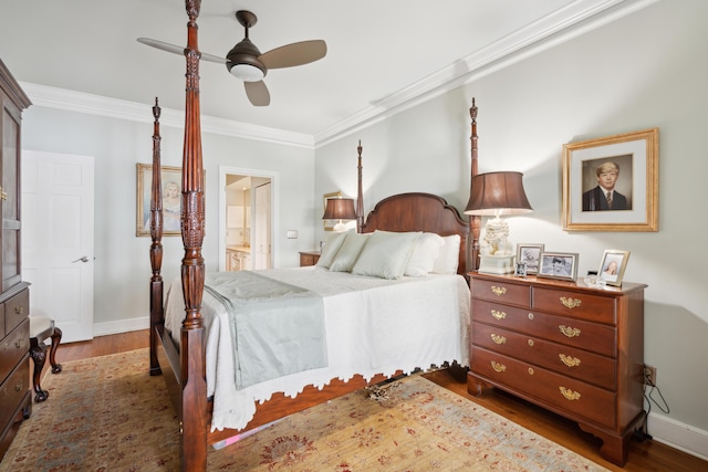 bedroom featuring crown molding, ceiling fan, ensuite bath, baseboards, and wood finished floors