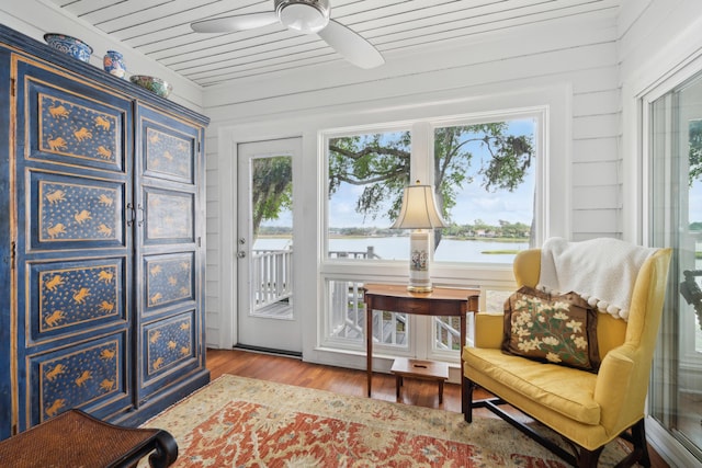 living area featuring a water view, ceiling fan, and wood finished floors