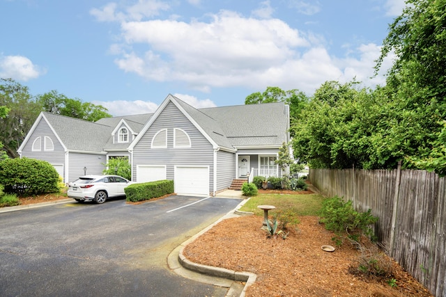 view of front of property with fence, a shingled roof, a garage, and aphalt driveway