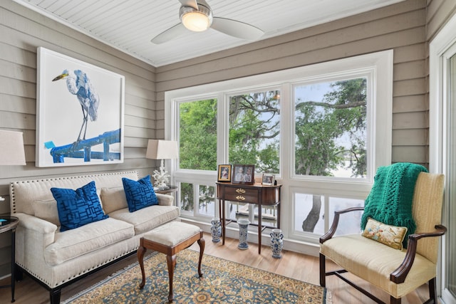 interior space featuring plenty of natural light, wood walls, ceiling fan, and wood finished floors