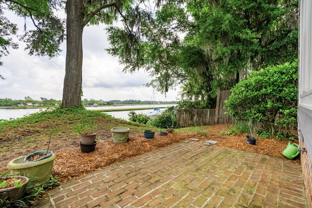 view of patio with a water view and fence