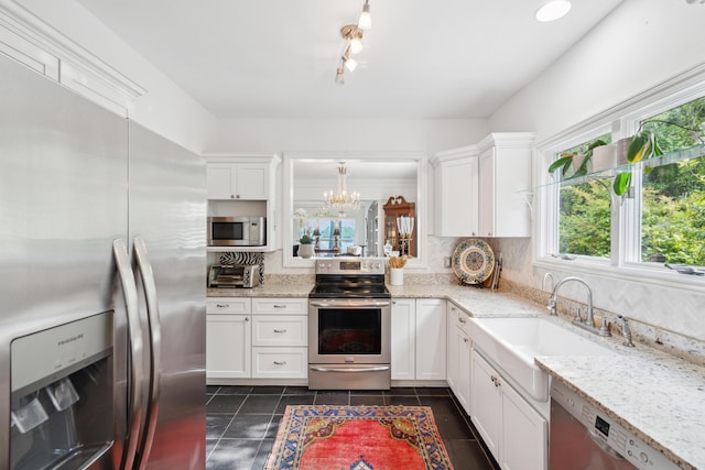 kitchen featuring white cabinets, appliances with stainless steel finishes, and an inviting chandelier