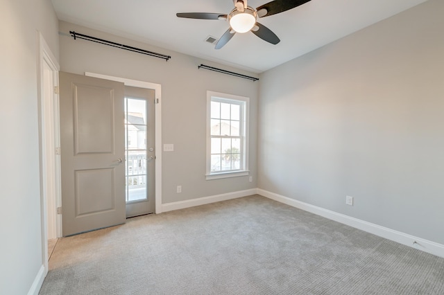 unfurnished room with baseboards, light carpet, visible vents, and a ceiling fan