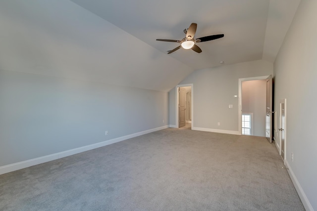 spare room with carpet flooring, ceiling fan, baseboards, and vaulted ceiling