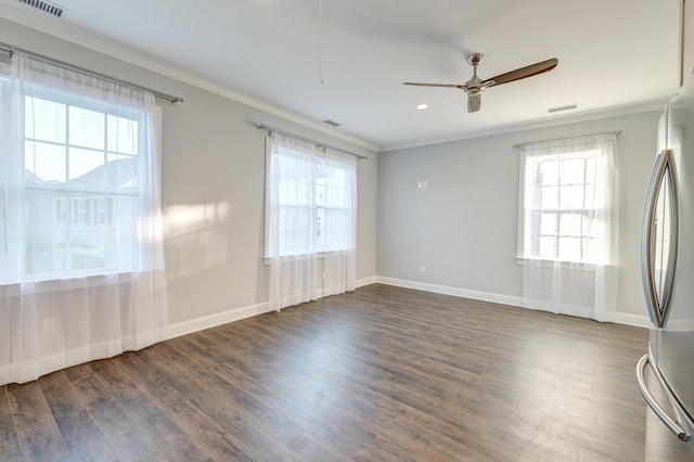 empty room featuring a healthy amount of sunlight, crown molding, and wood finished floors