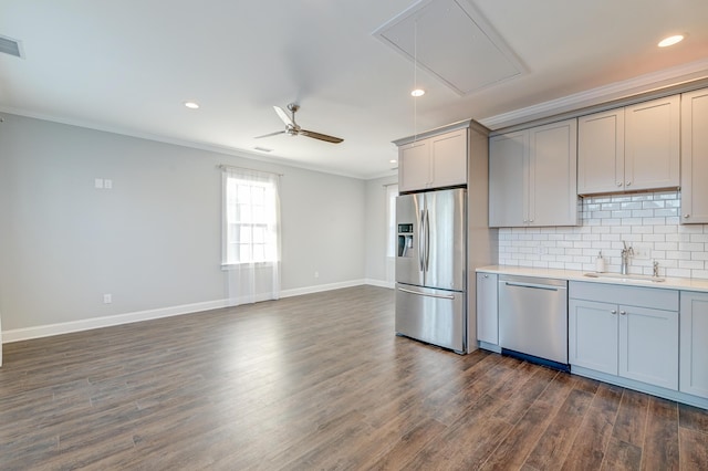 kitchen with tasteful backsplash, ornamental molding, gray cabinets, stainless steel appliances, and a sink