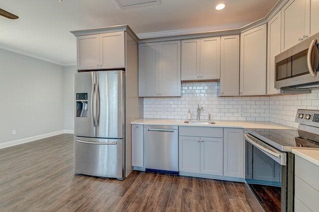 kitchen with gray cabinetry, a sink, stainless steel appliances, crown molding, and decorative backsplash