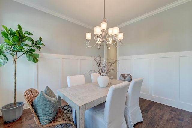 dining space featuring a wainscoted wall, dark wood finished floors, crown molding, a decorative wall, and a notable chandelier