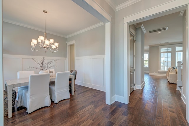 dining space with dark wood-type flooring, an inviting chandelier, wainscoting, and crown molding