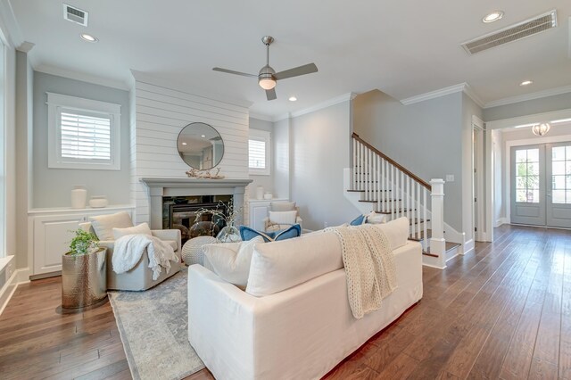 living room featuring visible vents, a healthy amount of sunlight, a glass covered fireplace, and stairway