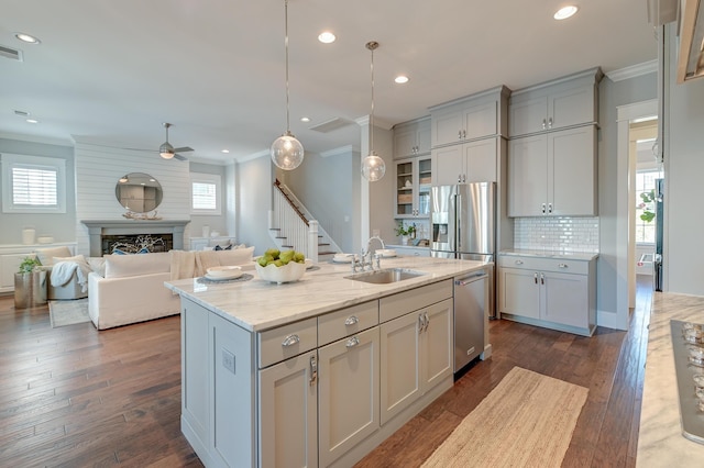 kitchen with a sink, appliances with stainless steel finishes, a fireplace, and crown molding