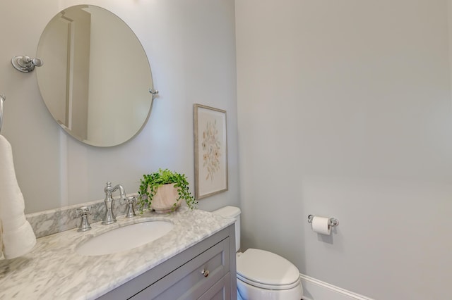 bathroom featuring vanity, toilet, and baseboards