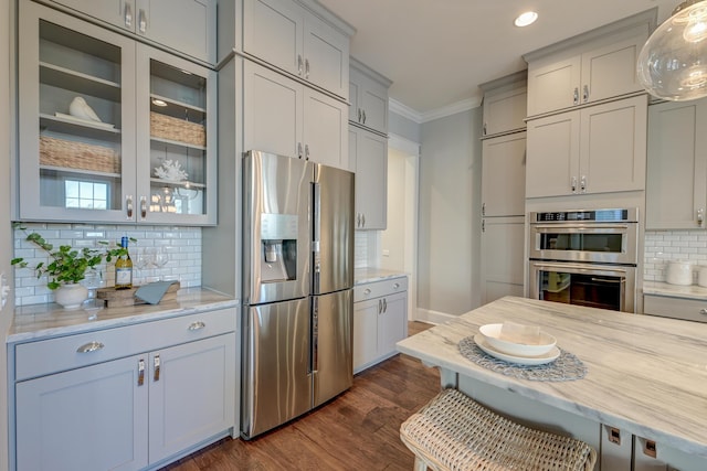 kitchen with dark wood finished floors, ornamental molding, decorative backsplash, glass insert cabinets, and appliances with stainless steel finishes