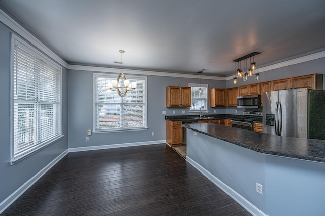 kitchen with ornamental molding, pendant lighting, stainless steel appliances, and a notable chandelier