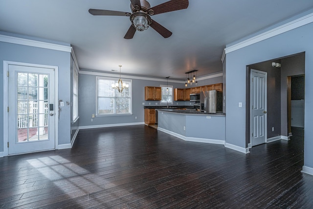 unfurnished living room featuring ceiling fan with notable chandelier, dark wood-type flooring, a wealth of natural light, and crown molding