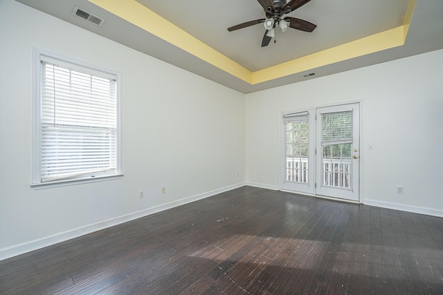 spare room featuring ceiling fan, a raised ceiling, and dark wood-type flooring