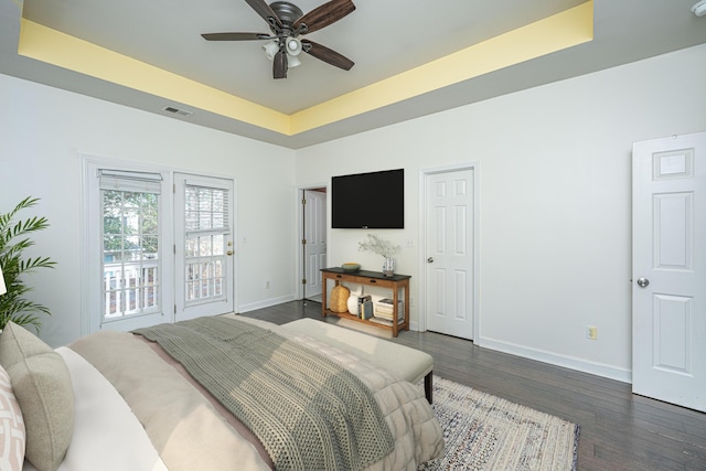 bedroom with a tray ceiling, ceiling fan, and dark wood-type flooring