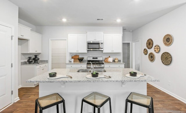 kitchen featuring appliances with stainless steel finishes, a kitchen island with sink, and white cabinets