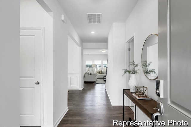 corridor with visible vents, baseboards, and dark wood-style flooring