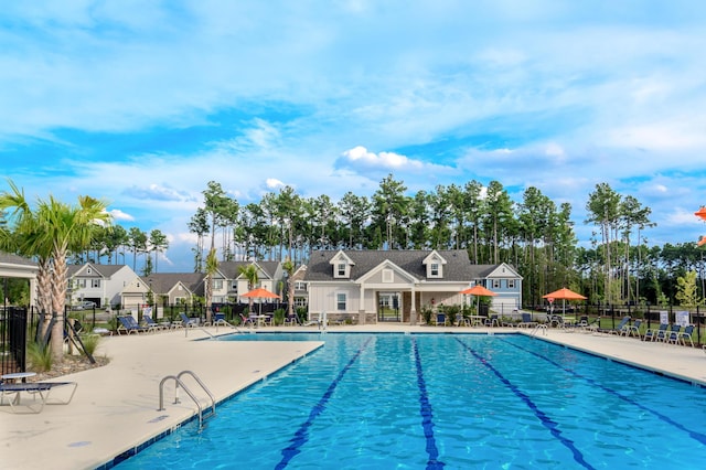 pool with a patio, fence, and a residential view