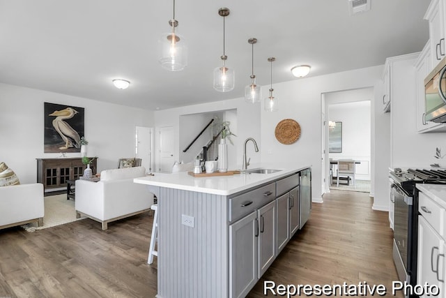 kitchen featuring visible vents, gray cabinetry, a sink, open floor plan, and stainless steel appliances