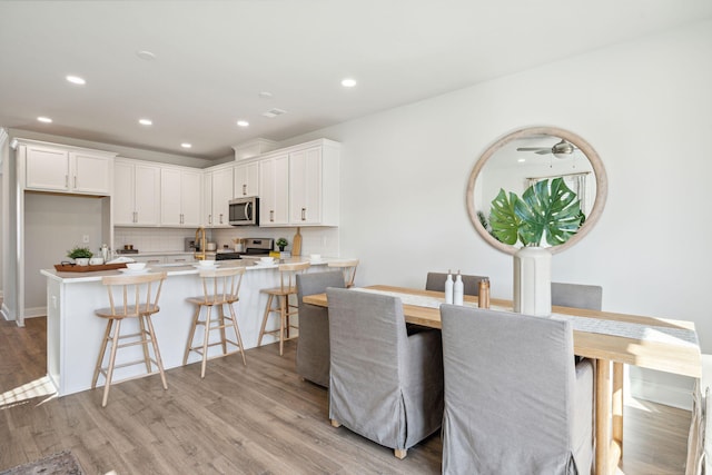 dining area with light hardwood / wood-style flooring and ceiling fan