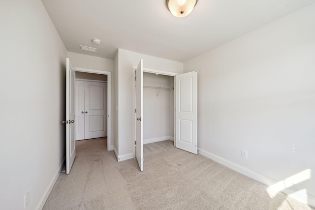 unfurnished bedroom with light carpet and a closet