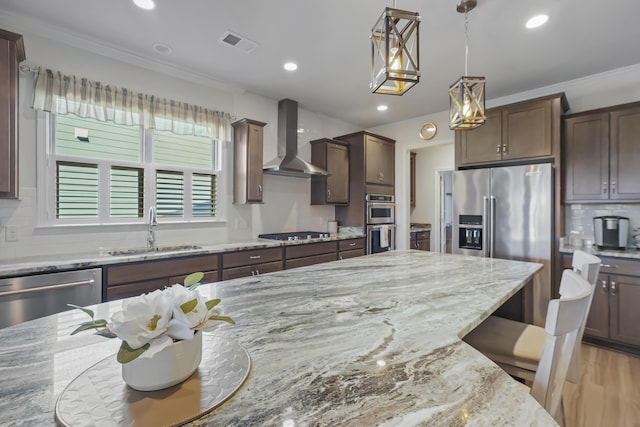 kitchen featuring stainless steel appliances, a breakfast bar, a sink, visible vents, and wall chimney range hood