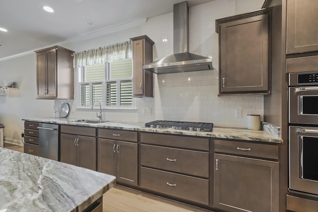 kitchen featuring stainless steel appliances, backsplash, ornamental molding, a sink, and wall chimney exhaust hood