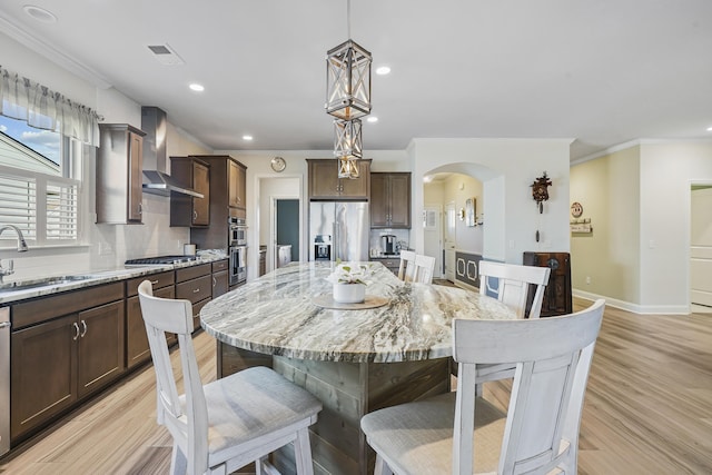 dining space with arched walkways, visible vents, baseboards, light wood finished floors, and crown molding