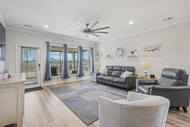 living room featuring light wood-type flooring, visible vents, a ceiling fan, and ornamental molding