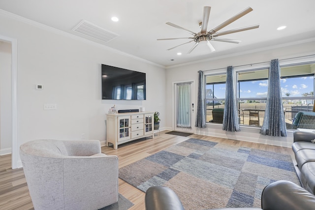 living area featuring plenty of natural light, visible vents, and crown molding