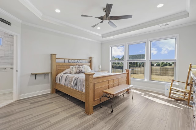 bedroom featuring ornamental molding, a raised ceiling, visible vents, and light wood-style flooring