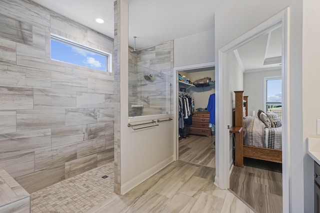 bathroom with baseboards, a spacious closet, crown molding, vanity, and a walk in shower