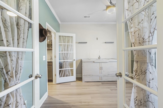 doorway with french doors, crown molding, visible vents, ceiling fan, and light wood-type flooring