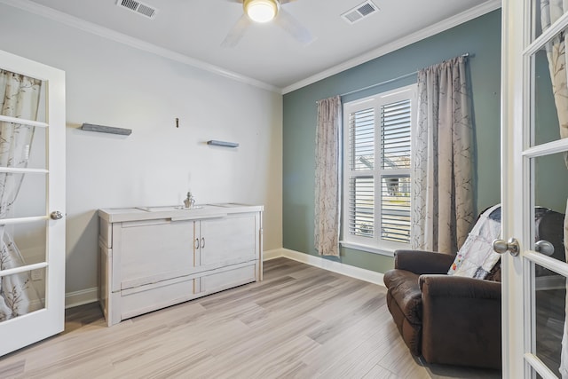 sitting room featuring light wood-style floors, visible vents, and crown molding