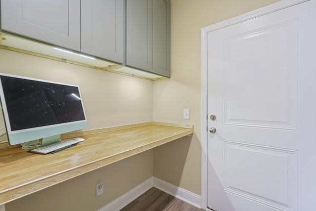 office space featuring dark wood finished floors, built in study area, and baseboards