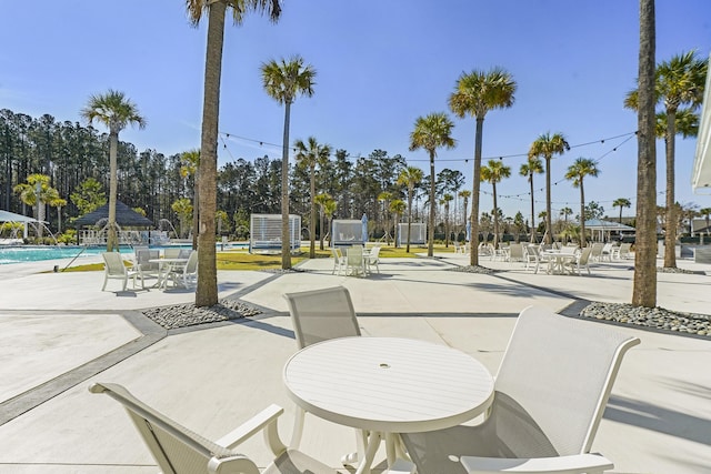 view of home's community with a swimming pool, outdoor dining area, and a patio