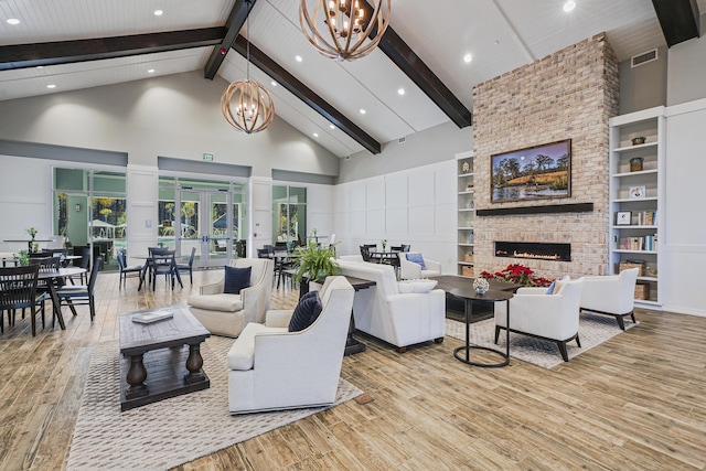 living room featuring visible vents, wood finished floors, an inviting chandelier, a brick fireplace, and high vaulted ceiling